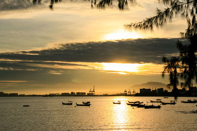 Silhouette sailboats in sea against sky during sunset