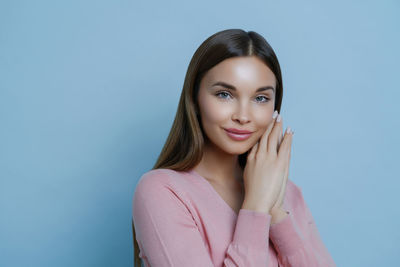 Portrait of young woman against blue background