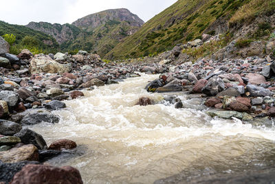 River flowing through rocks against sky