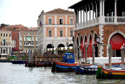 Boats moored in canal against buildings in city