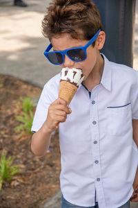 Cute child boy with a dirty face eats ice cream, the child enjoys dessert