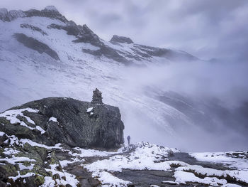 Big rock in front of snowcapped mountains.