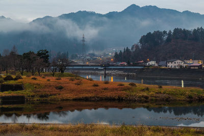 Scenic view of lake by trees and mountains against sky