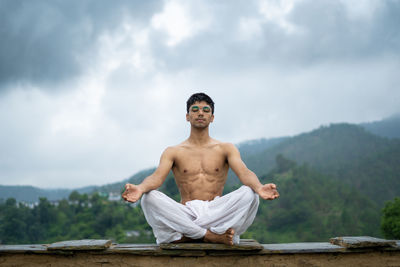 Full length of shirtless man standing against sky