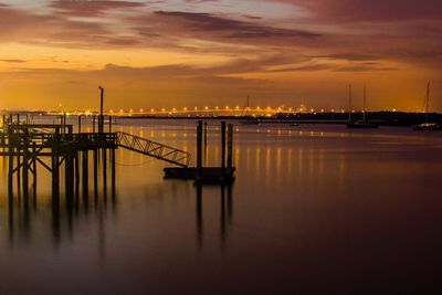 Pier over river against sky during sunset