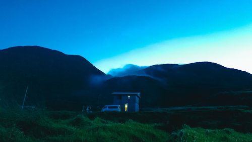 Scenic view of field and mountains against blue sky