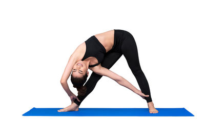 Full length of young woman with arms raised against white background