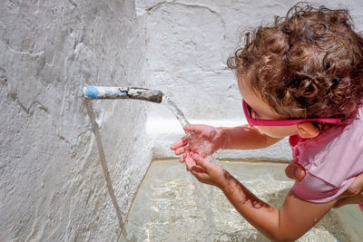 Close-up cute girl cleaning hands in running water outdoors