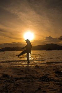 Silhouette man on beach against sky during sunset
