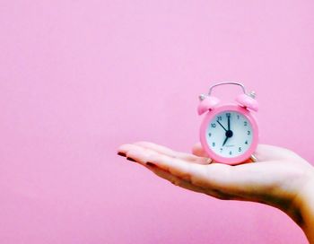 Close-up of woman hand against pink background