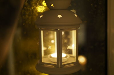 Close-up of illuminated lamp hanging on window