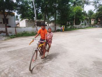 Full length of boys riding bicycle on road