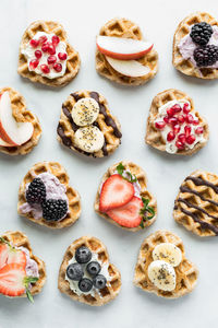 Heart shaped mini waffles with various toppings displayed in rows.