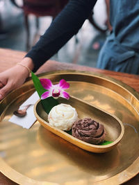Midsection of woman holding ice cream in plate on table