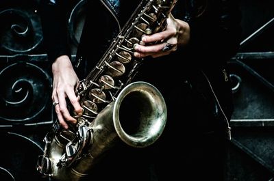 Midsection of person holding saxophone against metal door