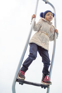 Low angle view of girl standing on play equipment at park against sky 