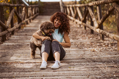 Side view of young woman sitting on footbridge