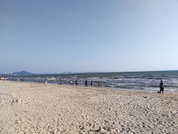 People on beach against clear sky