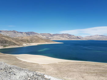 Scenic view of lake and mountains against clear blue sky