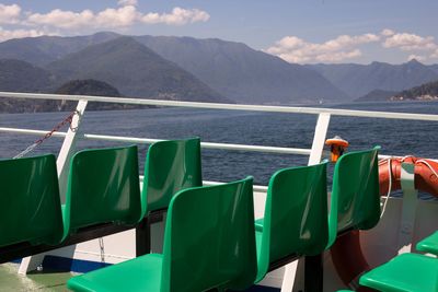 Chairs by sea against mountains