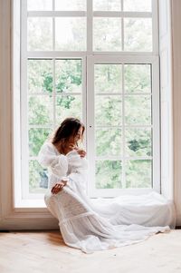 Bride sitting at window sill in room