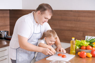 Loving father and little preschooler son cooking cut vegetables for salad