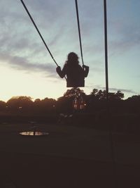 Silhouette of woman standing on tree trunk