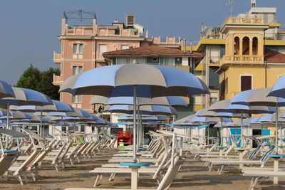 Deck chairs and parasols at beach against sky