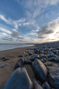 Rocks on beach against sky during sunset