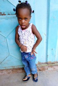 Portrait of cute girl standing against wall