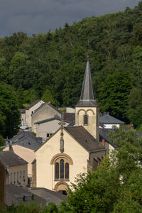 Church amidst trees and buildings against sky