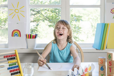 Portrait of happy girl sitting on table