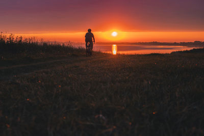 Man riding his gravel bike into the sunrise on the baltic sea coast