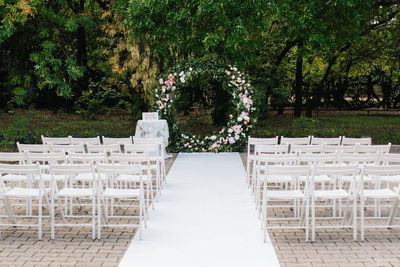 Empty chairs and table against trees in park