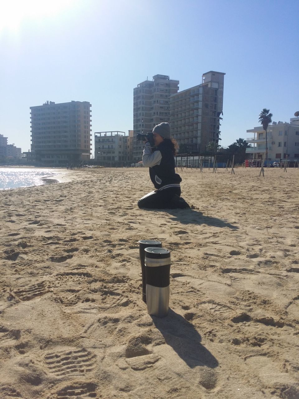 beach, sand, city, sea, one person, outdoors, built structure, real people, architecture, water, building exterior, day, sky, skyscraper, nature, people, adult, one man only