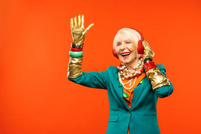 Smiling senior woman listening music against red background