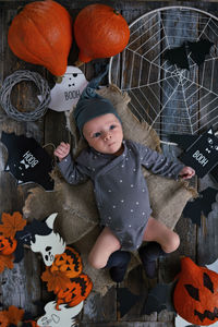 High angle view of cute baby boy lying with halloween's decoration wreath and garland 