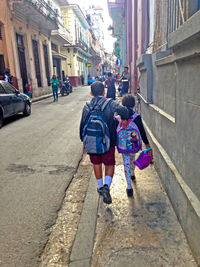 Rear view of people walking on street amidst buildings