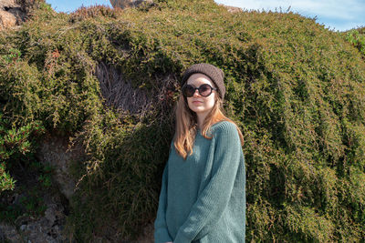 Beautiful young woman wearing sunglasses against plants