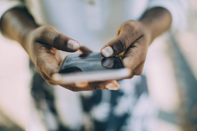 Midsection of young woman using smart phone while standing outdoors