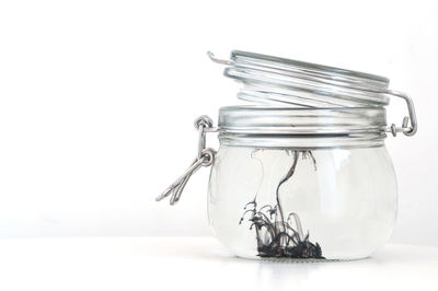 Close-up of glass jar on table against white background