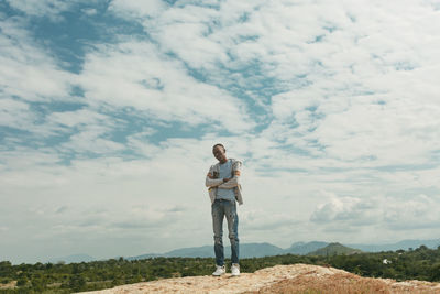 A man on top of a hill looking at camera against blue sky