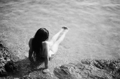 High angle view of woman sitting on shore at beach