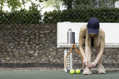 Sports woman getting ready and preparing for playing a game of tennis tying laces of shoes outdoor