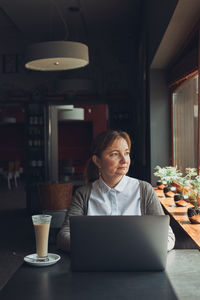 Relaxed businesswoman working remotely on her laptop computer contemplate managing her work