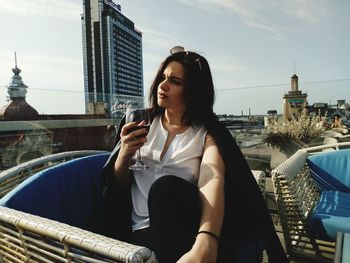 Woman holding drink sitting in city
