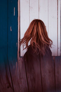 Digital composite image of woman tossing hair while standing against fence