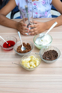 Cute indian chef girl preparing sundae dish as a part of non fire cooking which includes vanilla