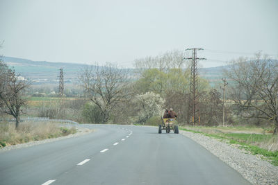 Man riding motorcycle on road against sky