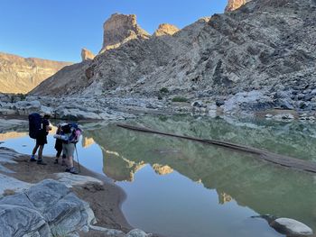 People on rock by mountain against sky